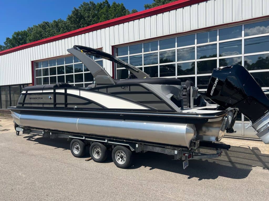 Bennington 25 QFBA pontoon boat displayed outside Hall's Sport Center, ready for water adventures.