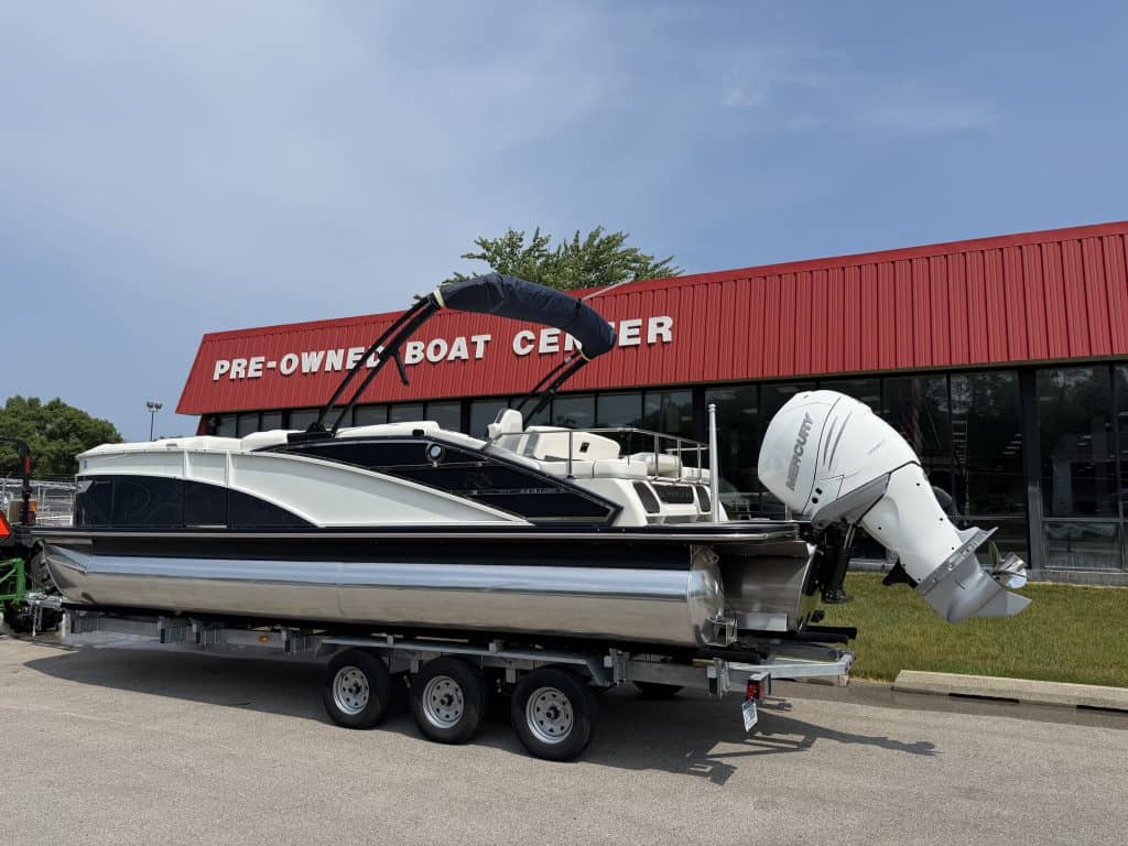 Pre-owned boat on trailer outside Hall's Sport Center, a boat dealership and rental facility.