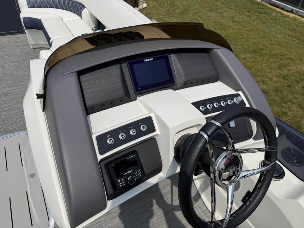 Boat helm with navigation screens and steering wheel, ideal for watercraft enthusiasts.