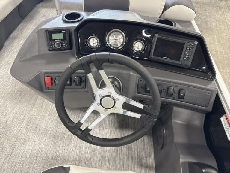 Close-up of the Bennington 22 SSR boat dashboard with steering wheel and gauges.