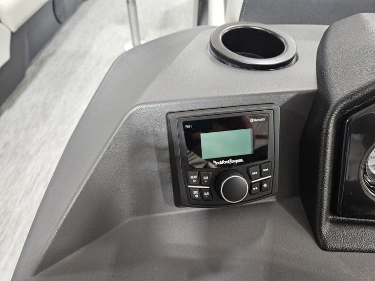 Close-up of boat dashboard with control panel and cup holder.