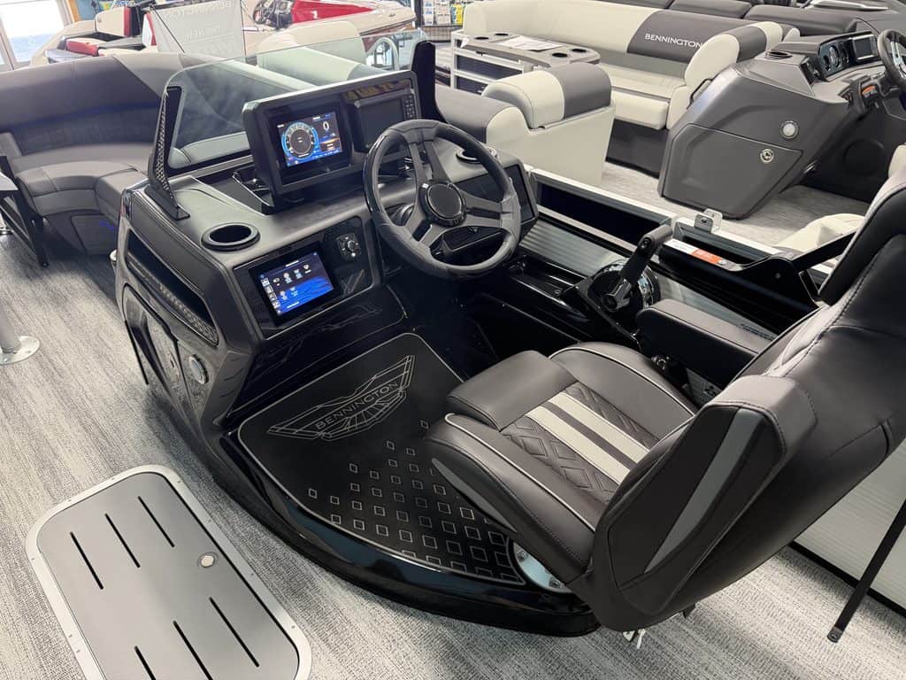 Modern boat helm station with digital displays and steering wheel.