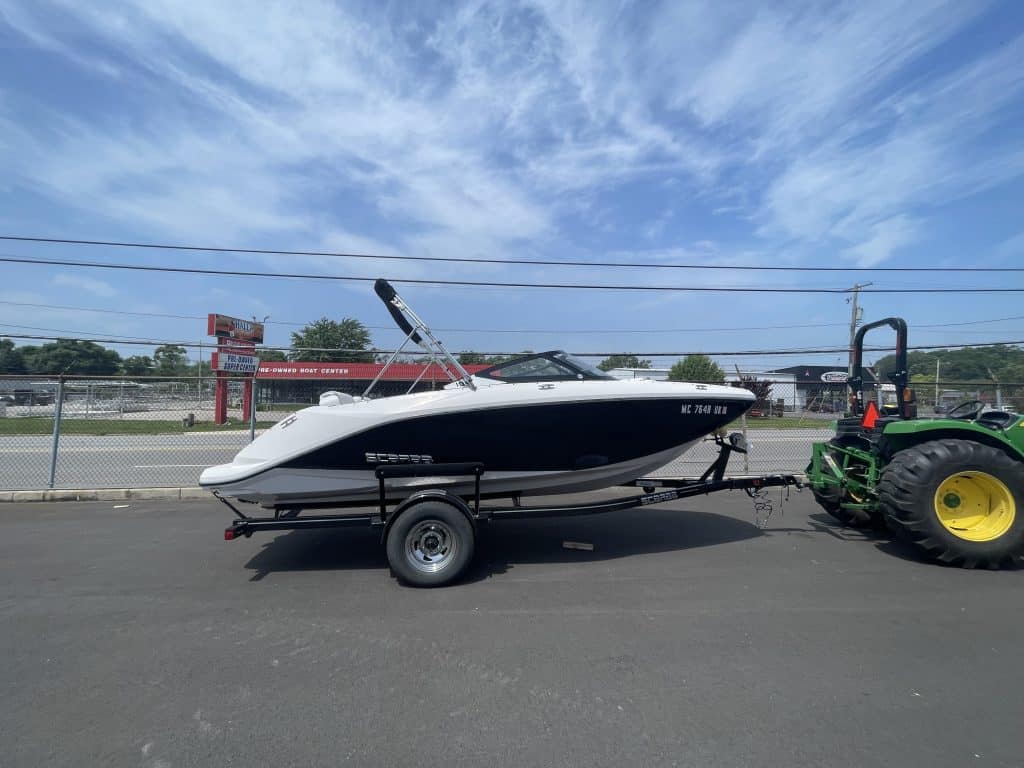 2018 Scarab 195 G boat attached to trailer on pavement under blue sky.