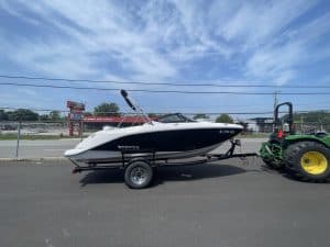 2018 Scarab 195 G boat attached to trailer on pavement under blue sky.