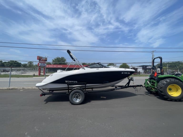 2018 Scarab 195 G boat attached to trailer on pavement under blue sky.