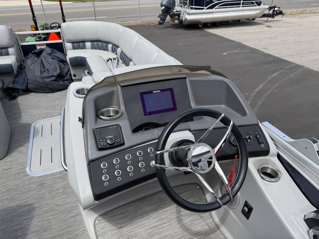 Pontoon boat dashboard with steering wheel and control panel at Hall's Sport Center.