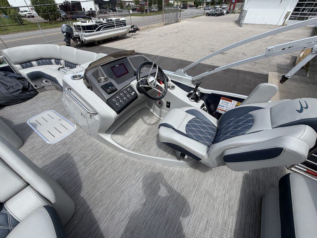 Luxury pontoon boat interior with captain's seat and control panel.