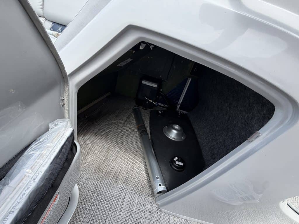 Open storage compartment of a Bennington 25QSB boat showing equipment inside.