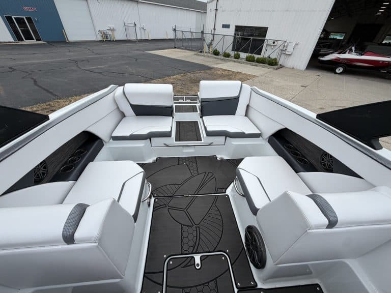Luxury boat seating area with white cushioned seats and speakers.