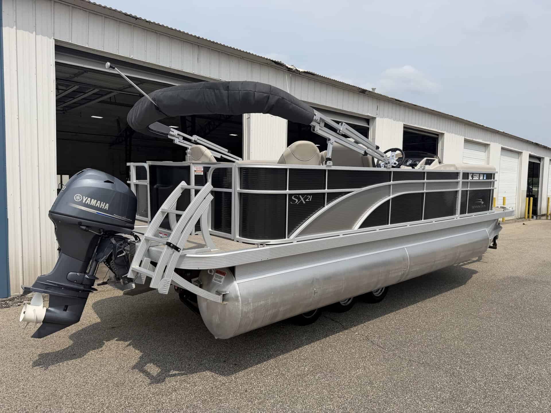 Bennington 21 SS pontoon boat with Yamaha engine outside a storage building.