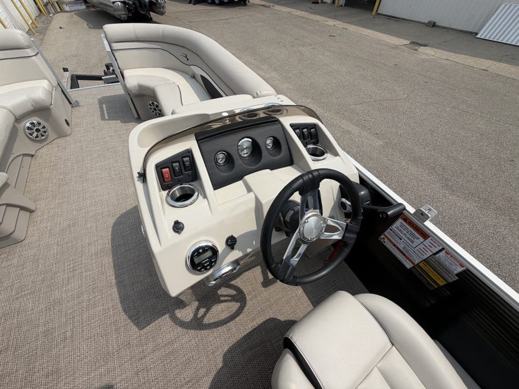 Pontoon boat dashboard with steering wheel and controls at Hall's Sport Center.