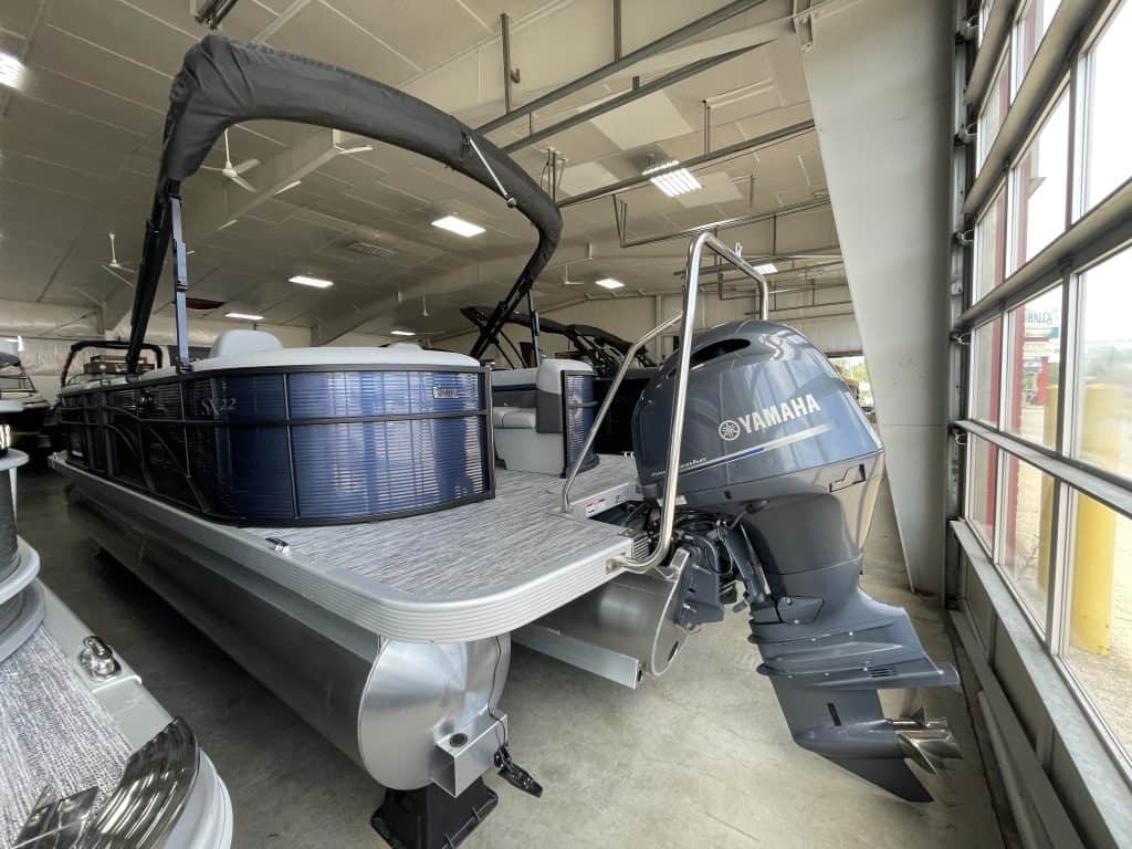 Modern pontoon boat displayed indoors at Hall's Sport Center, showcasing watercraft for sale or rent.