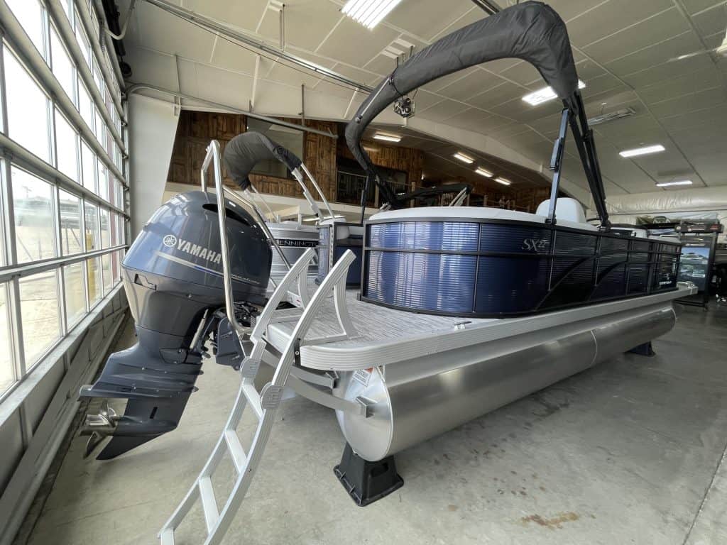 Pontoon boat with Yamaha outboard motor displayed indoors at Hall's Sport Center.