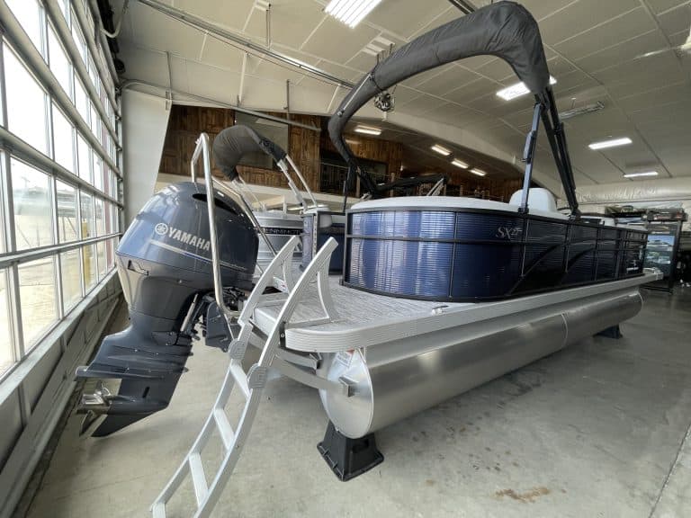 Pontoon boat with Yamaha outboard motor displayed indoors at Hall's Sport Center.
