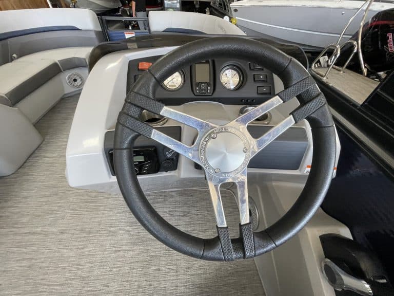 Boat steering wheel and dashboard with gauges and controls at Hall's Sport Center, highlighting mari.