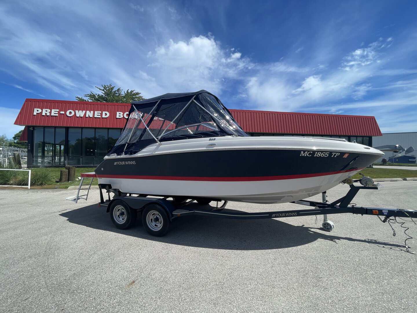Pre-owned Four Winns 215 SUNDOWNER boat on trailer at Hall's Sport Center.
