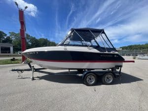 Black and white Four Winns 215 SUNDOWNER boat on trailer at marina.