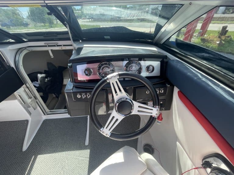 Boat dashboard with steering wheel and gauges inside a Four Winns 215 Sundowner.