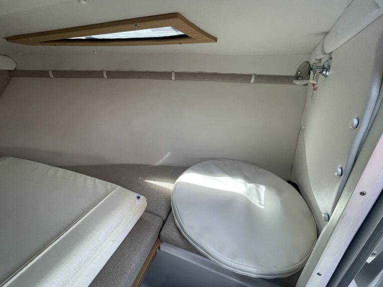 Boat cabin interior with a round table and sleeping area.