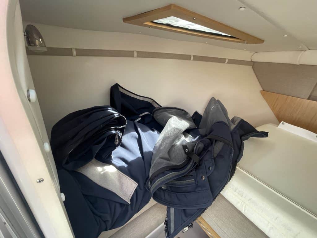 Clothing and bags stored in a small, enclosed space with a skylight.