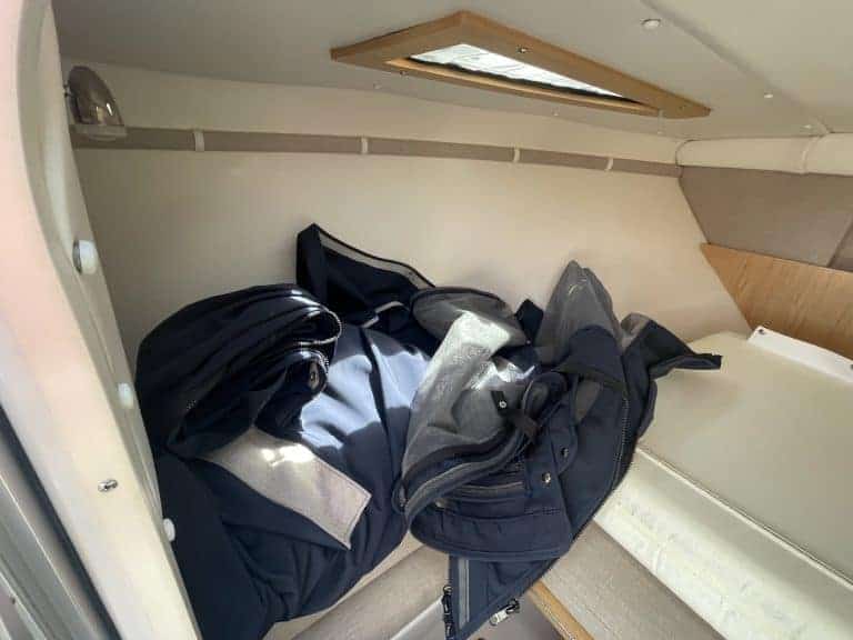 Clothing and bags stored in a small, enclosed space with a skylight.