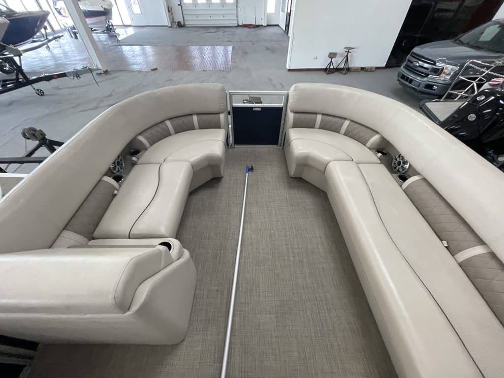 Luxury pontoon boat interior with beige seating and built-in speakers.