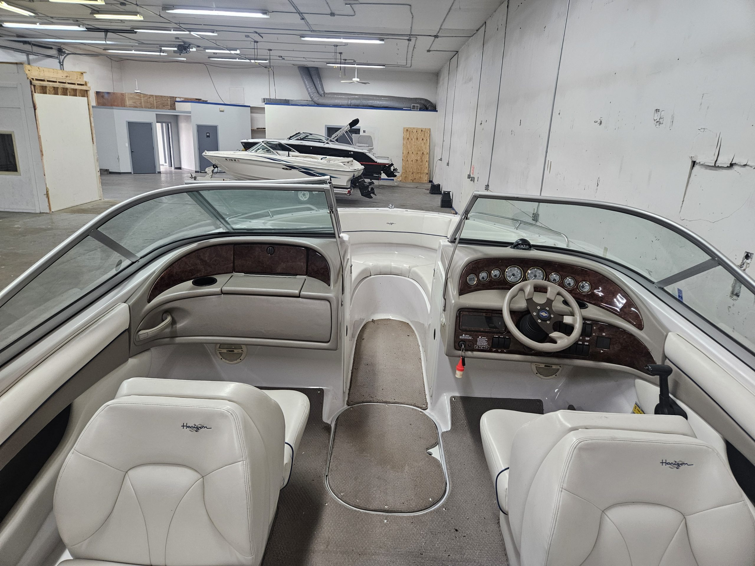 Boat interior with white seating and dashboard in a showroom or storage area.