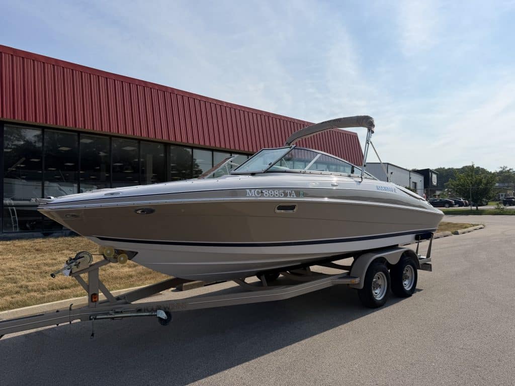 Four Winns H240 boat on trailer outside a building with red roof.
