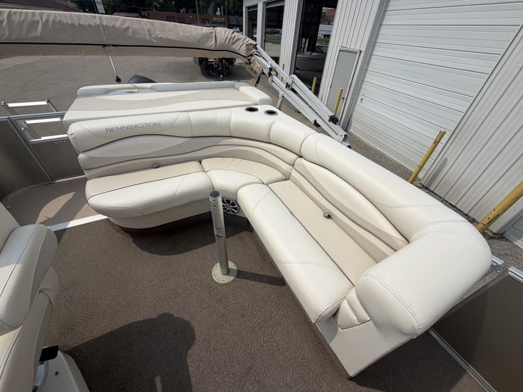 Luxury pontoon boat seating with white cushions and sunshade.