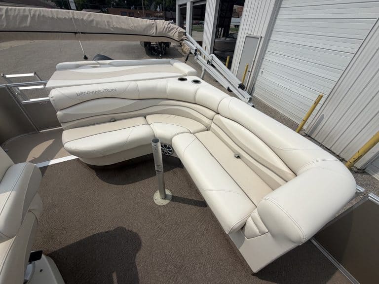Luxury pontoon boat seating with white cushions and sunshade.
