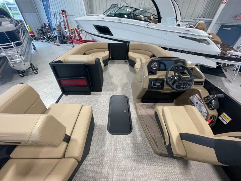 Elegant pontoon boat cockpit with beige seating and steering wheel at Hall's Sport Center.
