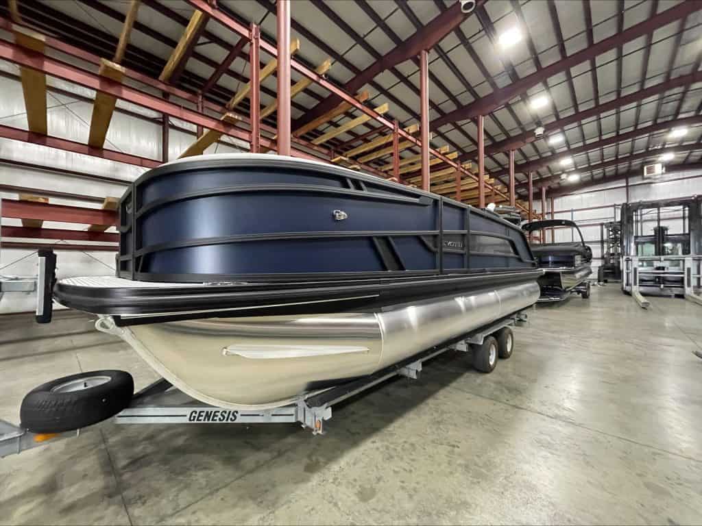 Pontoon boat on trailer inside Hall's Sport Center for sale or display.