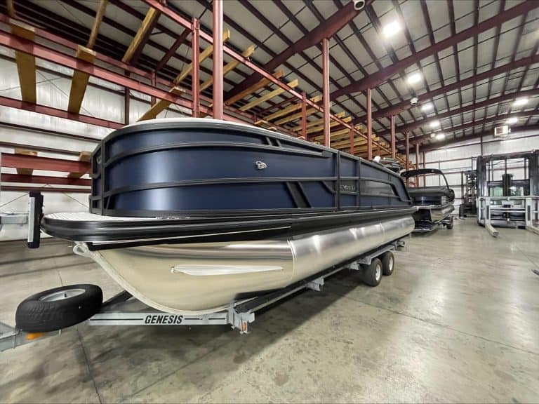 Pontoon boat on trailer inside Hall's Sport Center for sale or display.