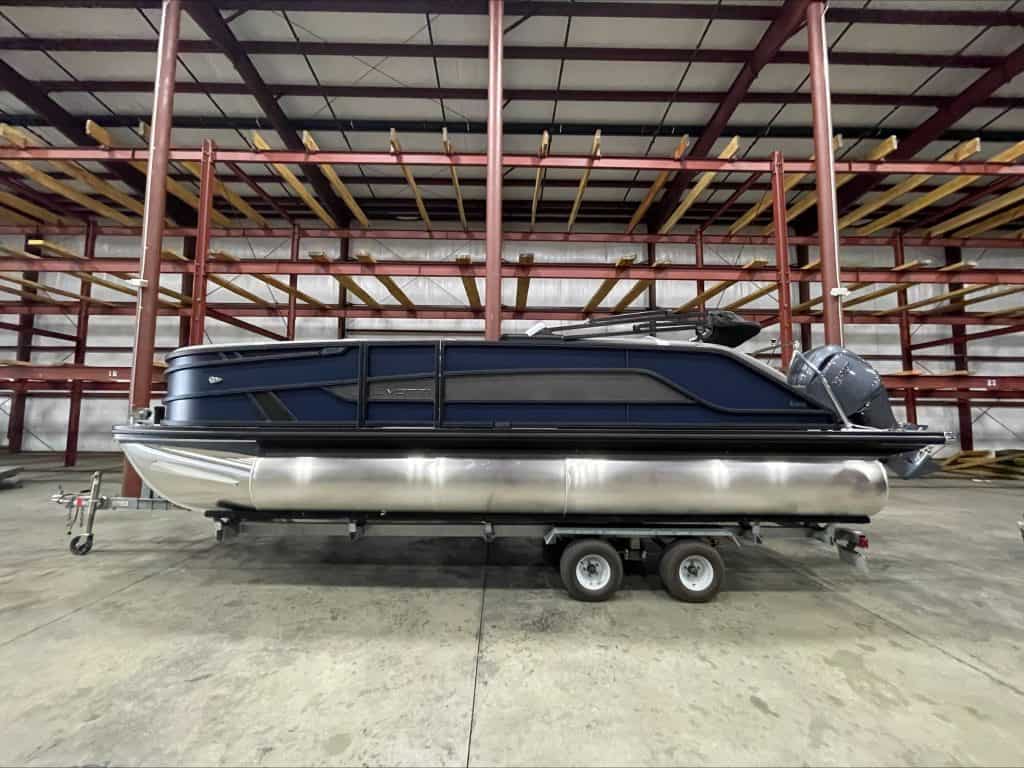 Luxury pontoon boat on trailer in indoor storage at Hall's Sport Center.