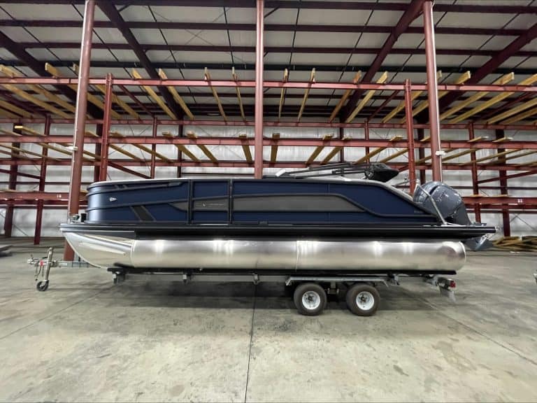 Luxury pontoon boat on trailer in indoor storage at Hall's Sport Center.
