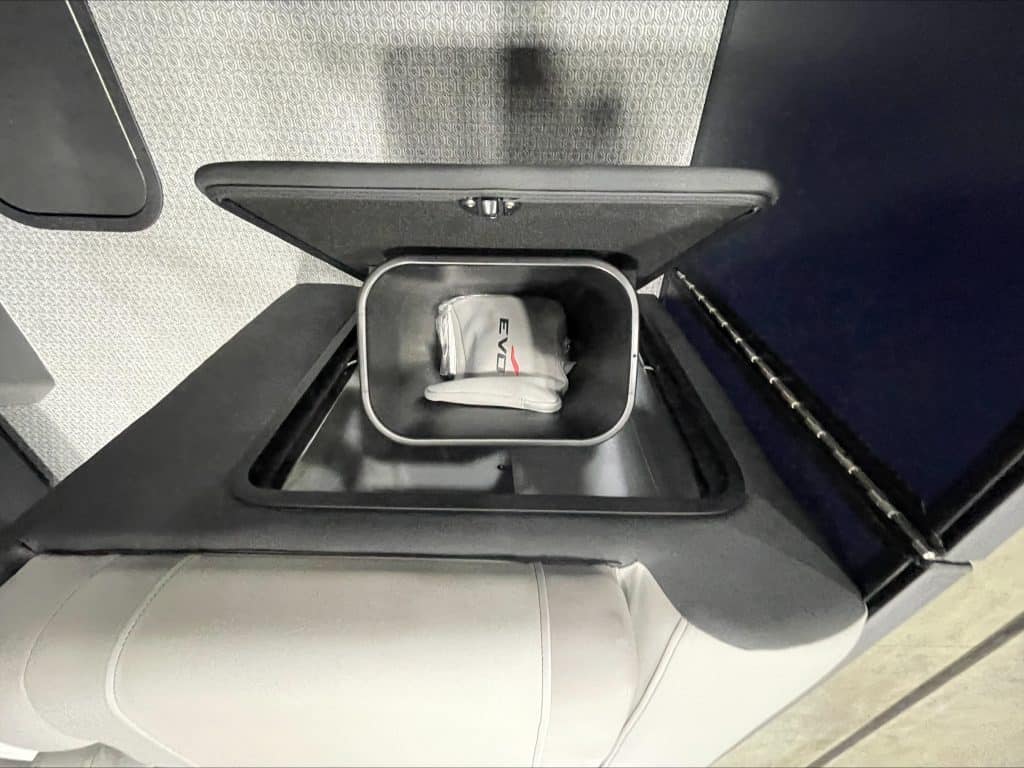 Storage compartment with a white EVOTTI 521CS shoe inside on a vehicle seat.