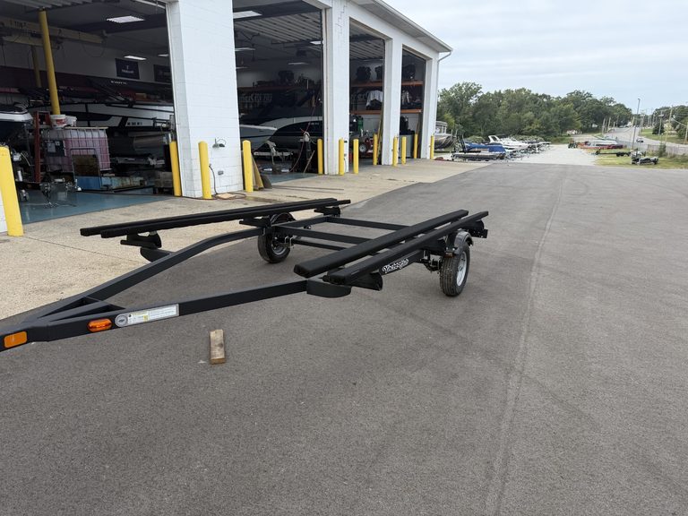 Boat trailer parked outside Hall's Sport Center with boats inside.