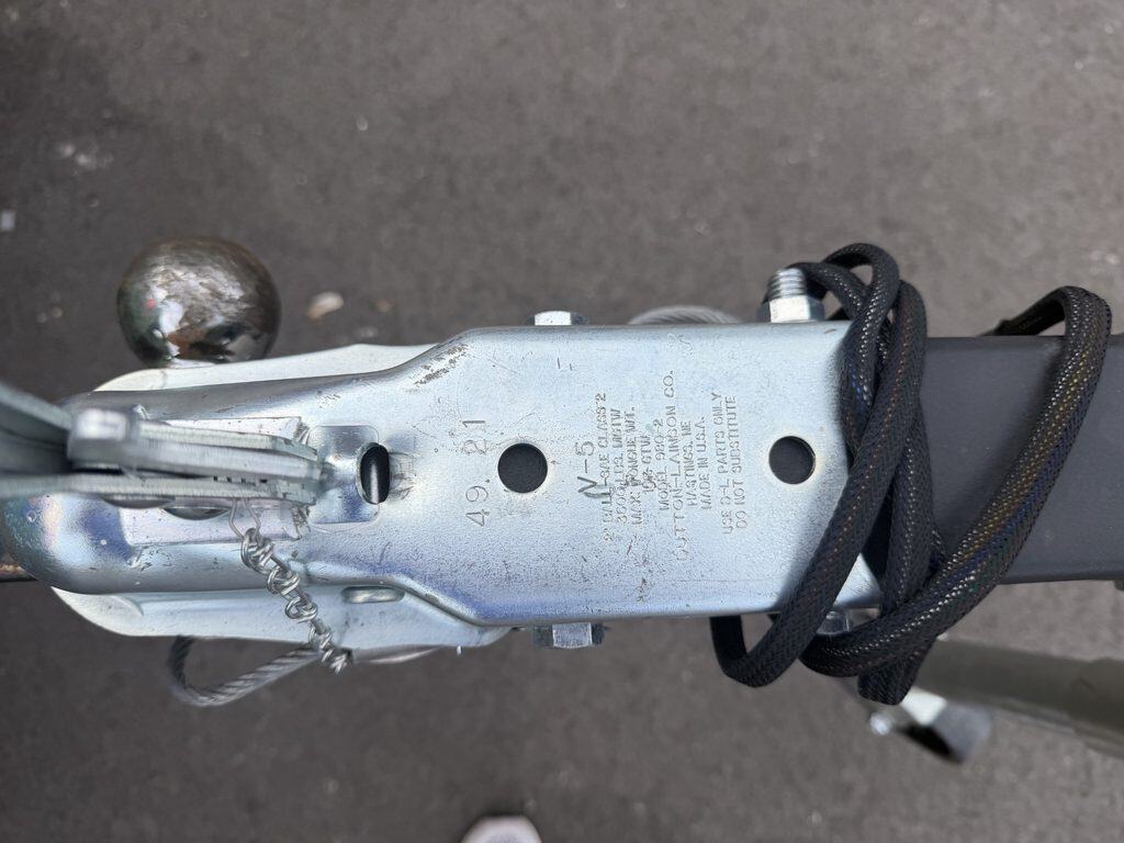 Close-up of boat trailer hitch and coupler with safety chains and wiring.
