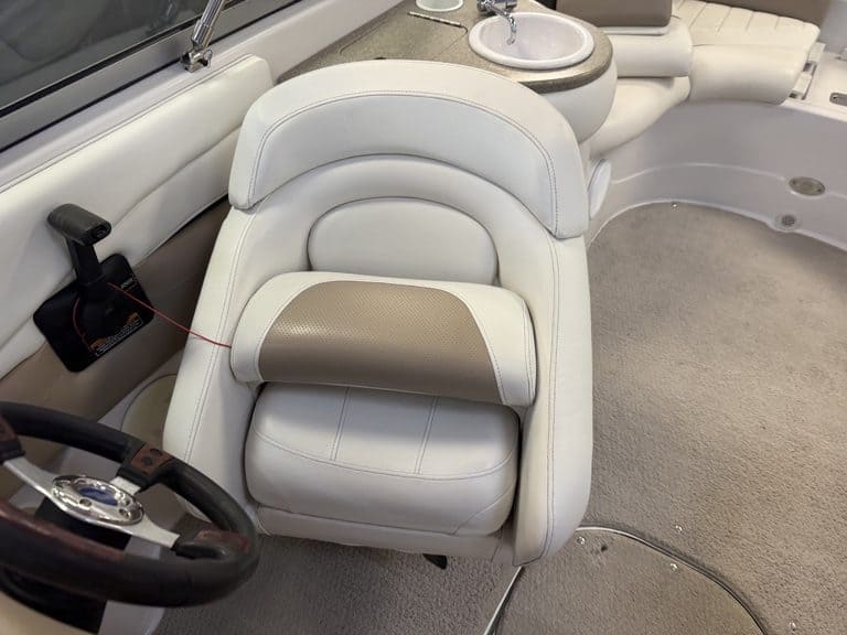 White boat captain seat with beige cushion on a boat interior.