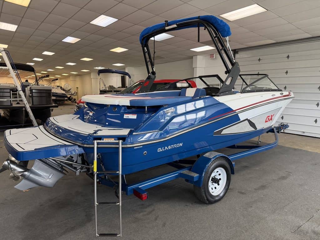 Blue and white Glastron GX215 boat on trailer inside showroom.