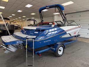 Blue and white Glastron GX215 boat on trailer inside showroom.