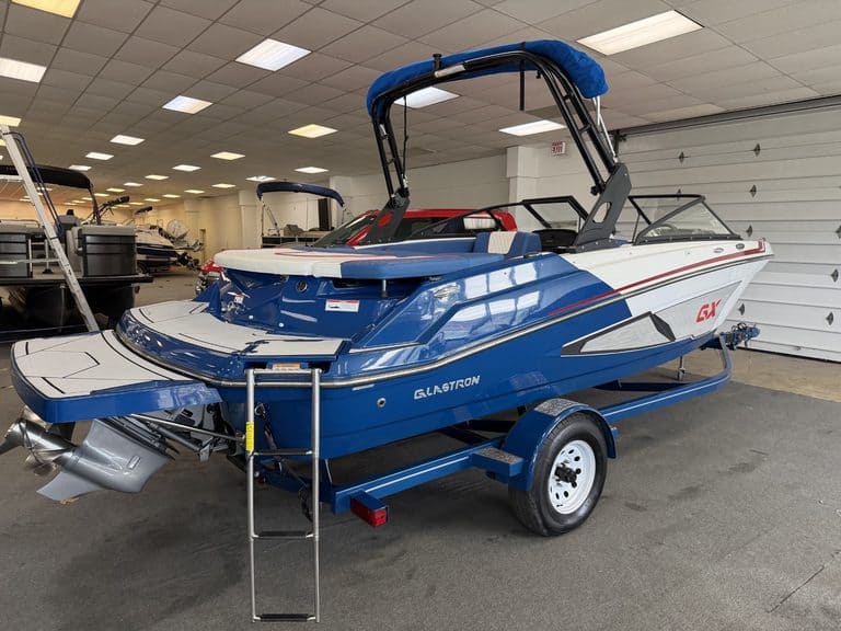 Blue and white Glastron GX215 boat on trailer inside showroom.
