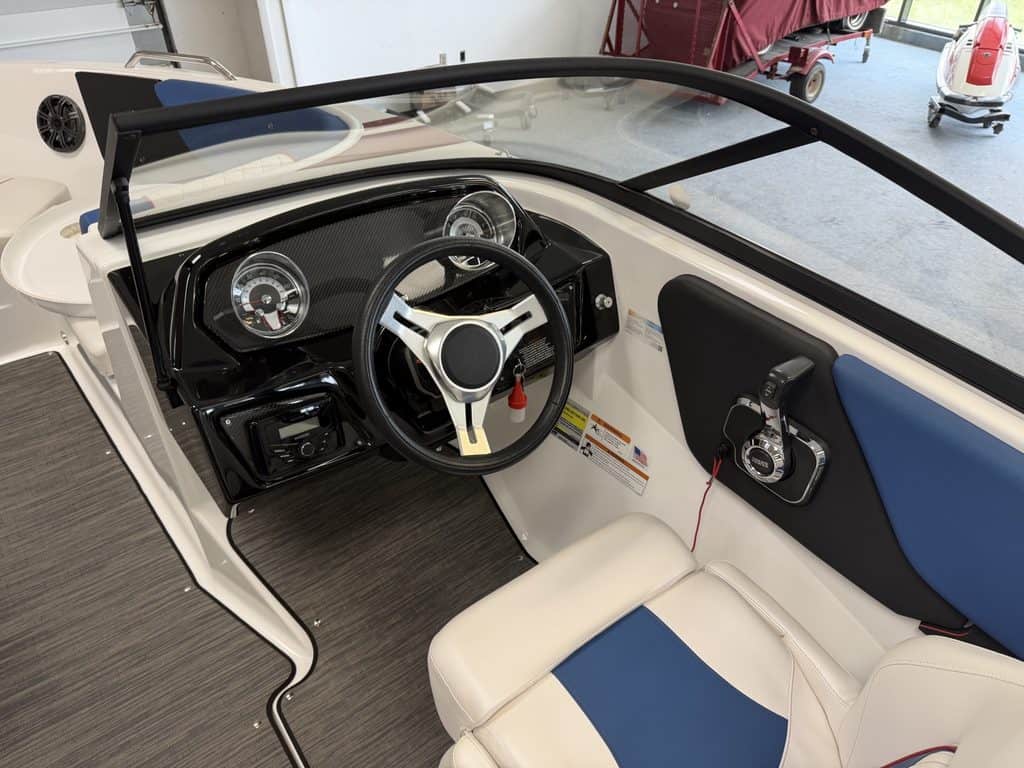 Close-up of the steering wheel and dashboard of a Glastron GX215 boat.