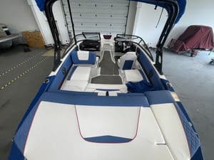 2021 Glastron GX215 boat in showroom with seating and steering wheel.