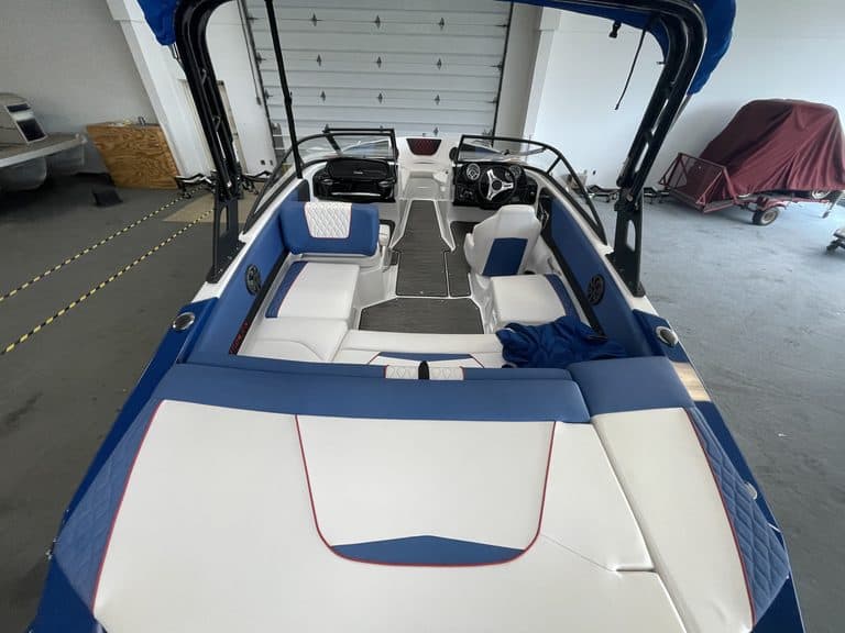 2021 Glastron GX215 boat in showroom with seating and steering wheel.