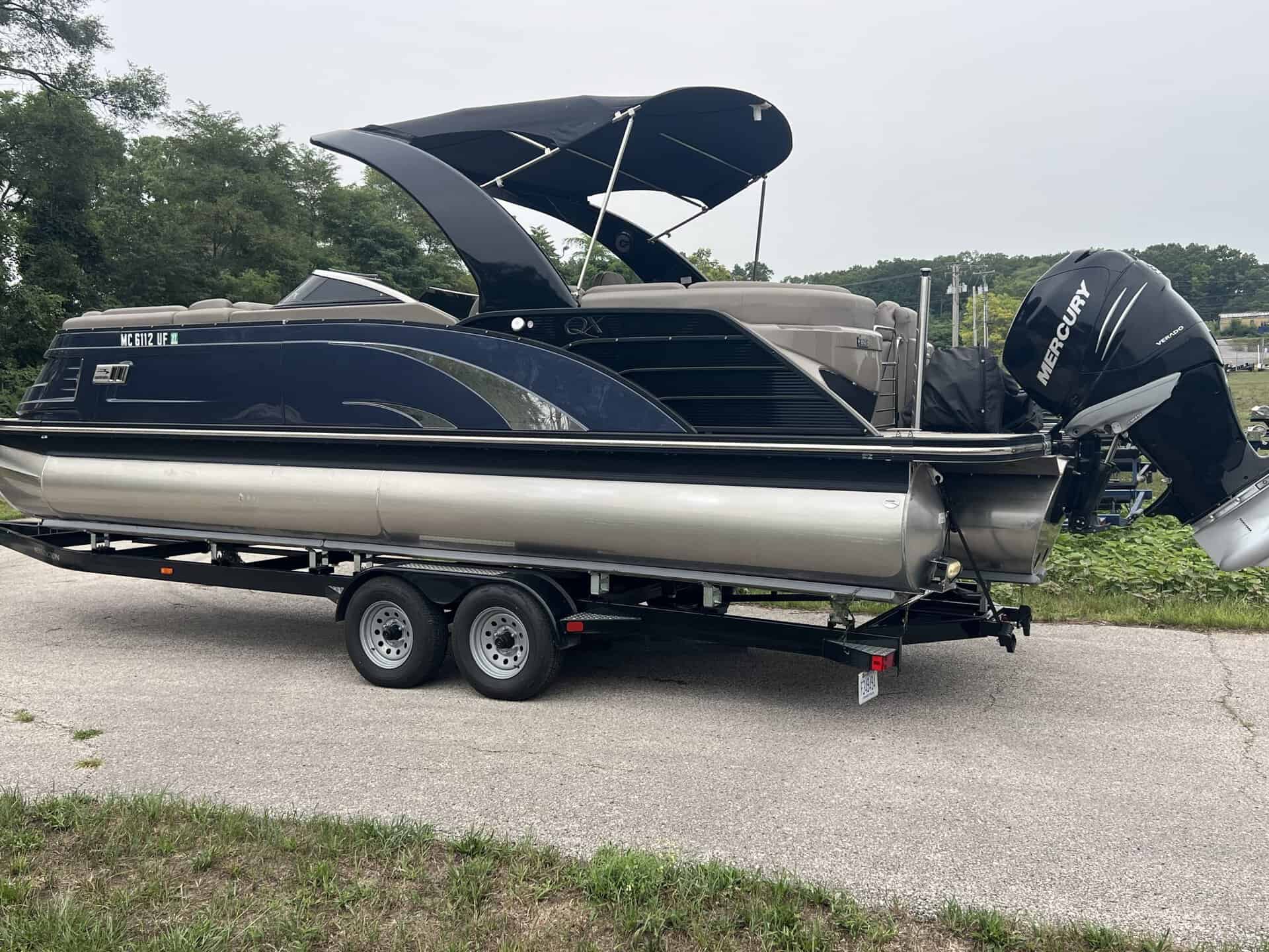 Bennington pontoon boat with Mercury outboard motor on trailer.