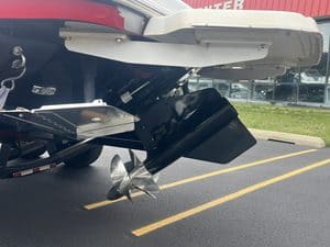 Close-up of a boat's outboard motor and stern in a parking lot.