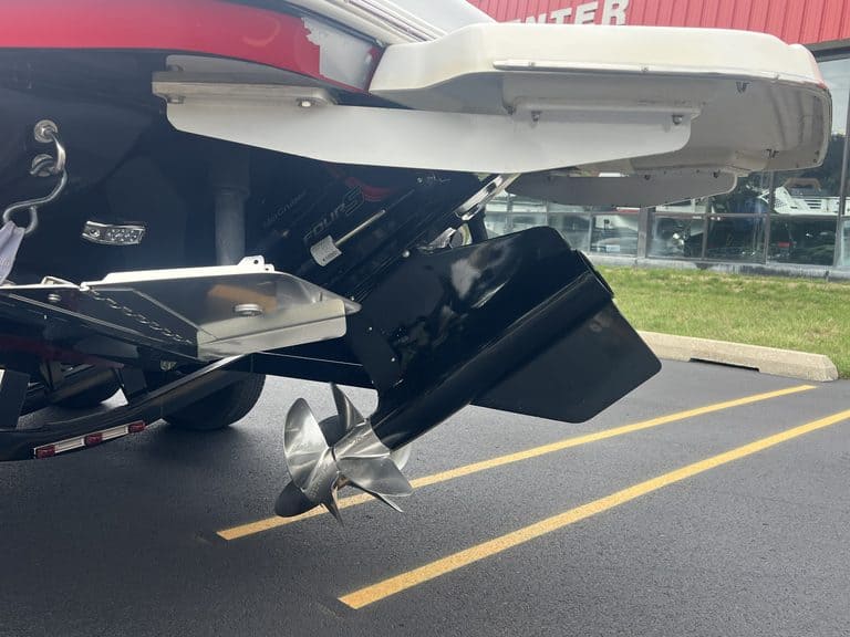 Close-up of a boat's outboard motor and stern in a parking lot.