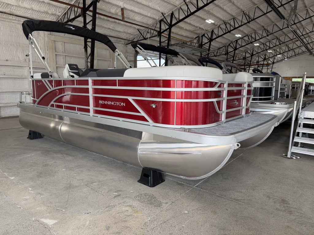 Red and white Bennington pontoon boat inside a showroom.