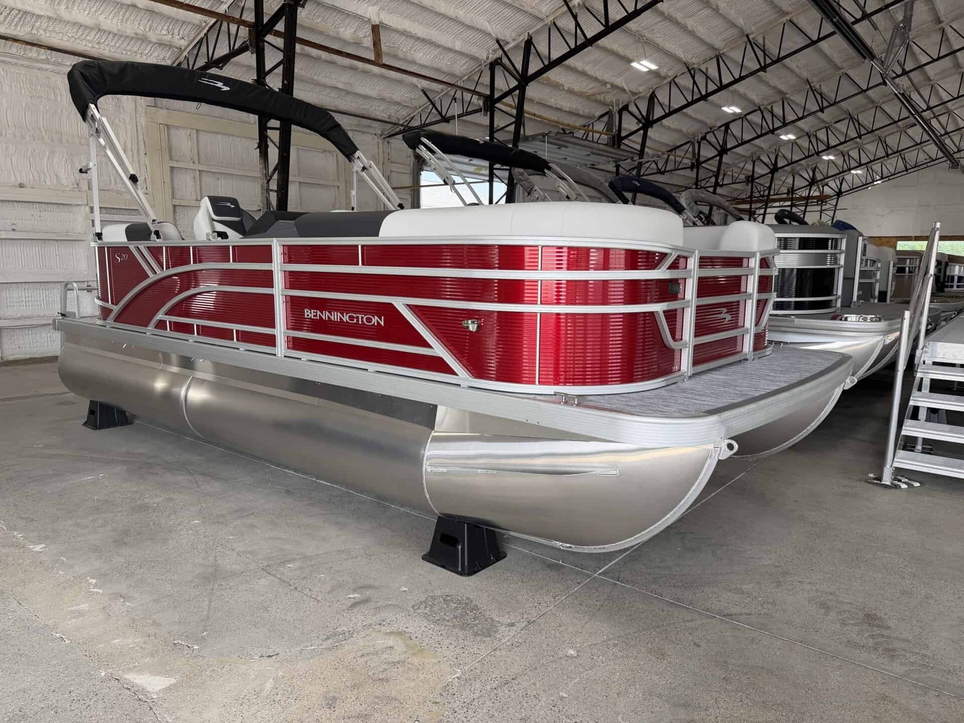 Red and white Bennington pontoon boat inside a showroom.